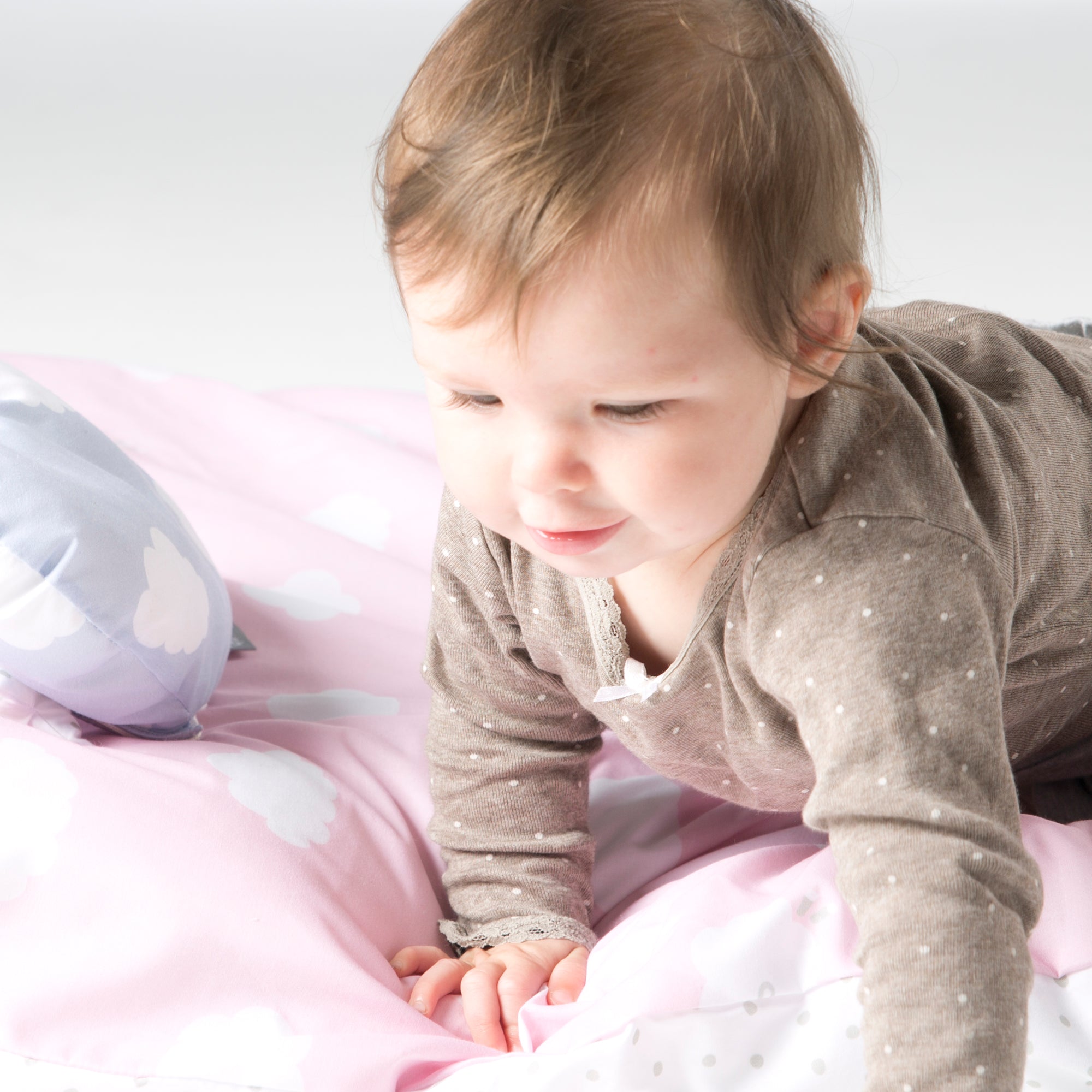 Vorschaubild Kollektion Kleine Wolke in Rosa / Weiß - Detailaufnahme mit Baby auf Bettwäsche in Rosa mit Wolkenprint