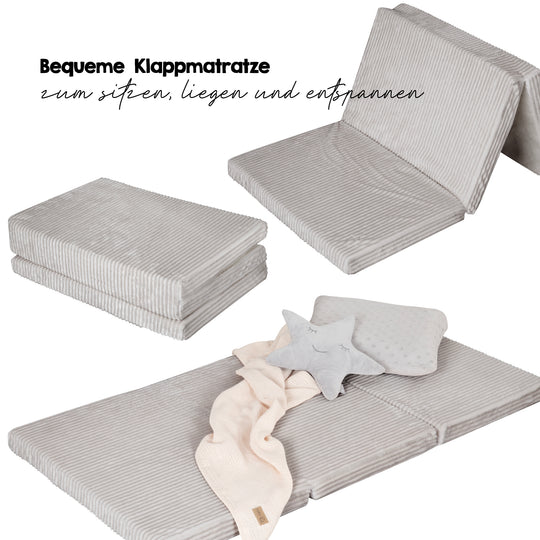 Reisebettmatratze in Grau zusammengefaltet, aufgeklappt und ausgelegt, Schriftzug 'Bequeme Klappmatratze zum Sitzen, Liegen und Entspannen'.