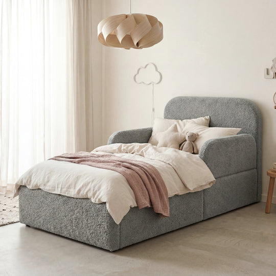 Grey bouclé children's bed with fall protection, cushion, cuddly toy and cloud light in a children's room. Fully AI-generated.