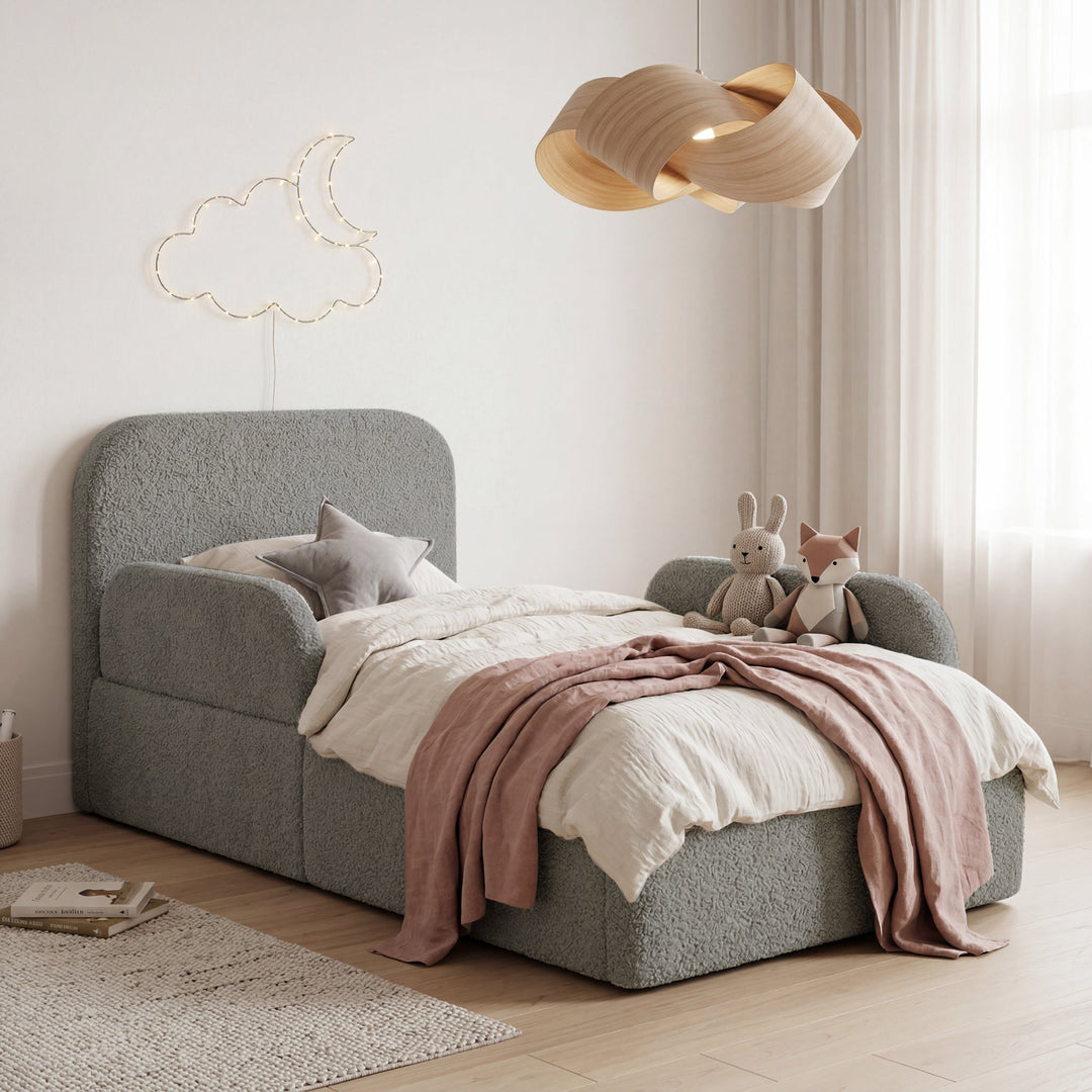 Grey bouclé children's bed with fall protection, cuddly toys and moon-and-cloud fairy lights in a children's room. Fully AI-generated.