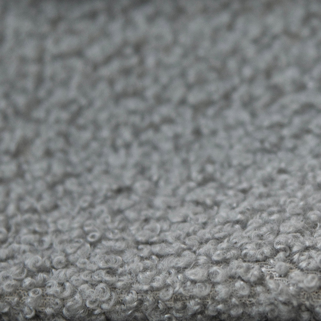 Close-up of the grey, textured bouclé fabric cover of the children's bed.