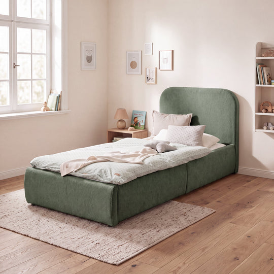 Green bouclé children's bed in a bright children's room with picture wall and bookshelf. Fully AI-generated.