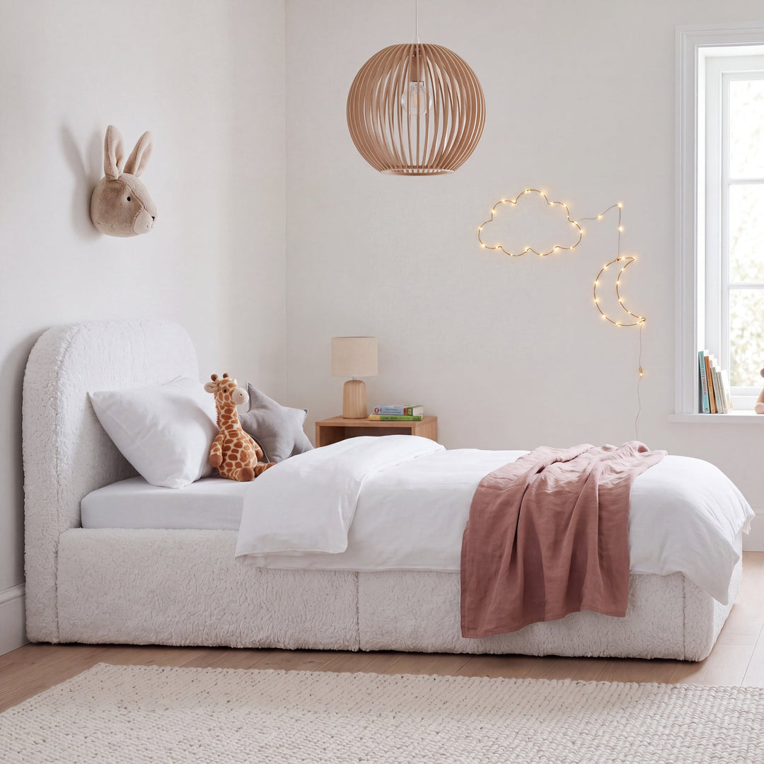 White bouclé children's bed with cuddly toys, pendant lamp and cloud-and-moon fairy lights in the room. Fully AI-generated.