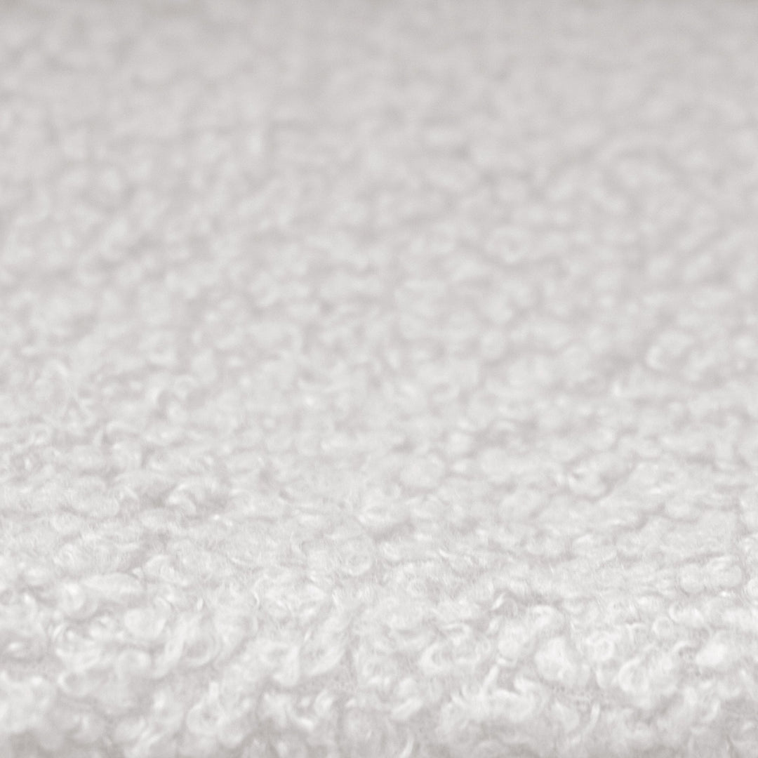 Close-up of the white, textured bouclé fabric cover of the children's bed.