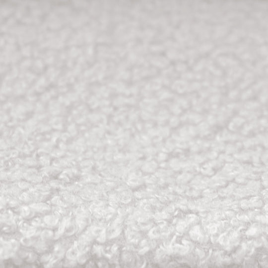 Close-up of the white, textured bouclé fabric cover of the children's bed.