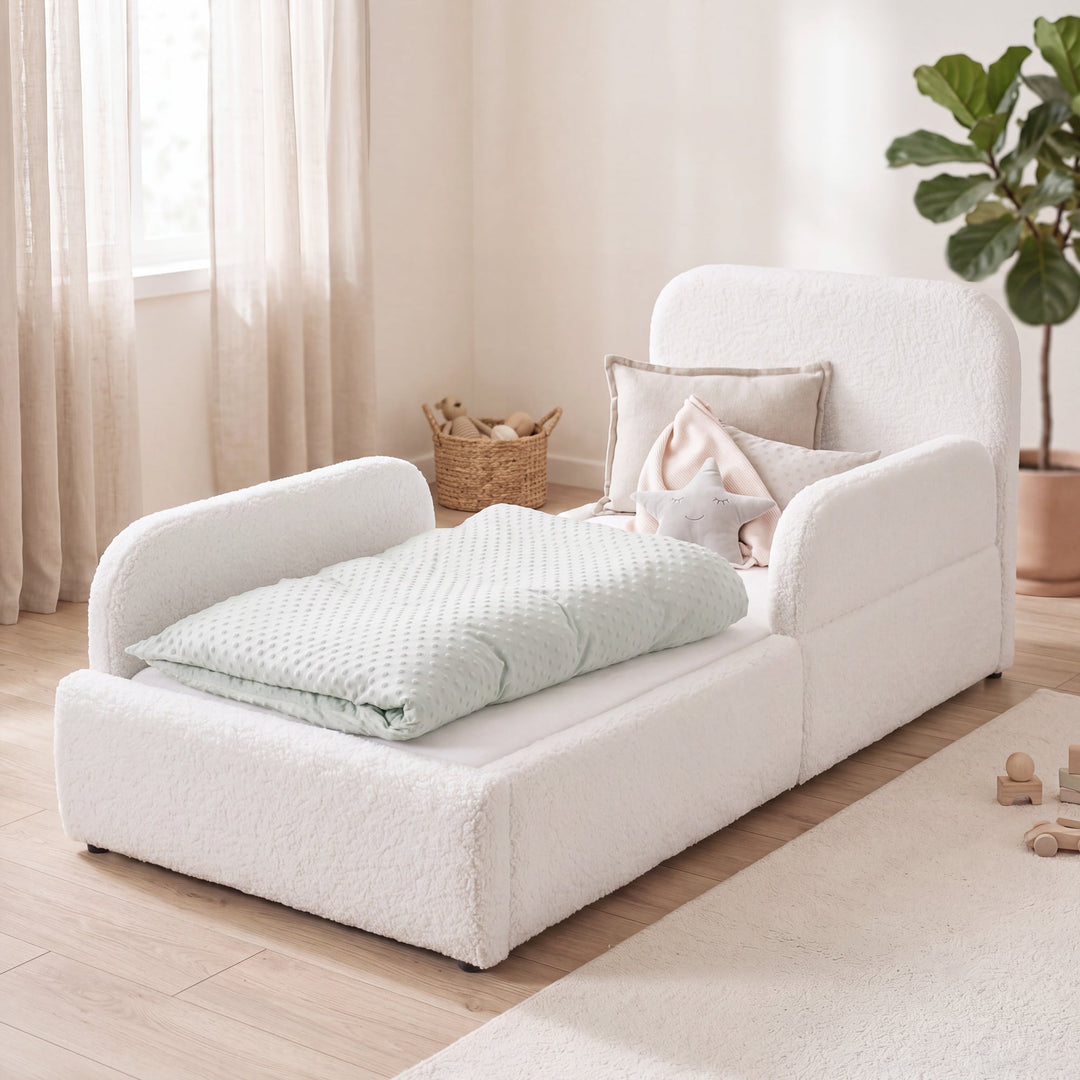 White bouclé children's bed with fall protection, rattan basket and plant in a bright room. Fully AI-generated.