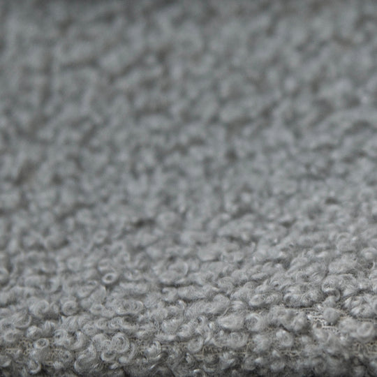 Primo piano del rivestimento in tessuto bouclé grigio e strutturato del letto.