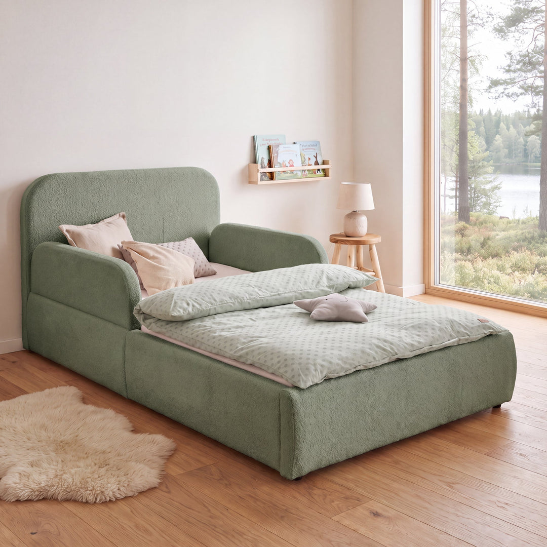 Letto per bambini roba Little Dream verde in una cameretta con vista lago, libreria e tappeto in pelle di pecora. Interamente generata con IA.