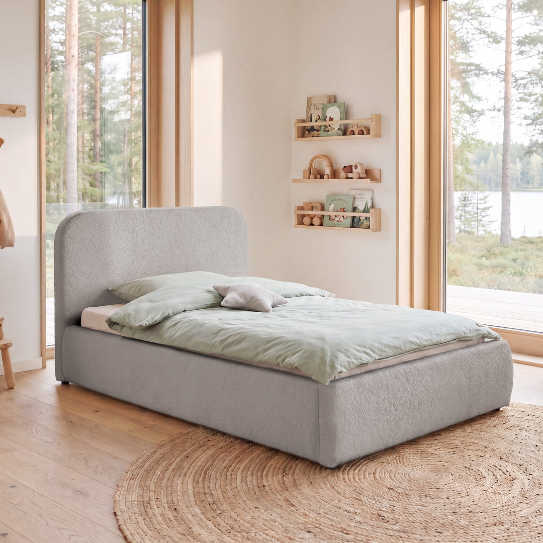 Cama infantil roba Little Dream gris claro en una habitación infantil con vistas al bosque y ropa de cama verde menta. Generada parcialmente con IA.