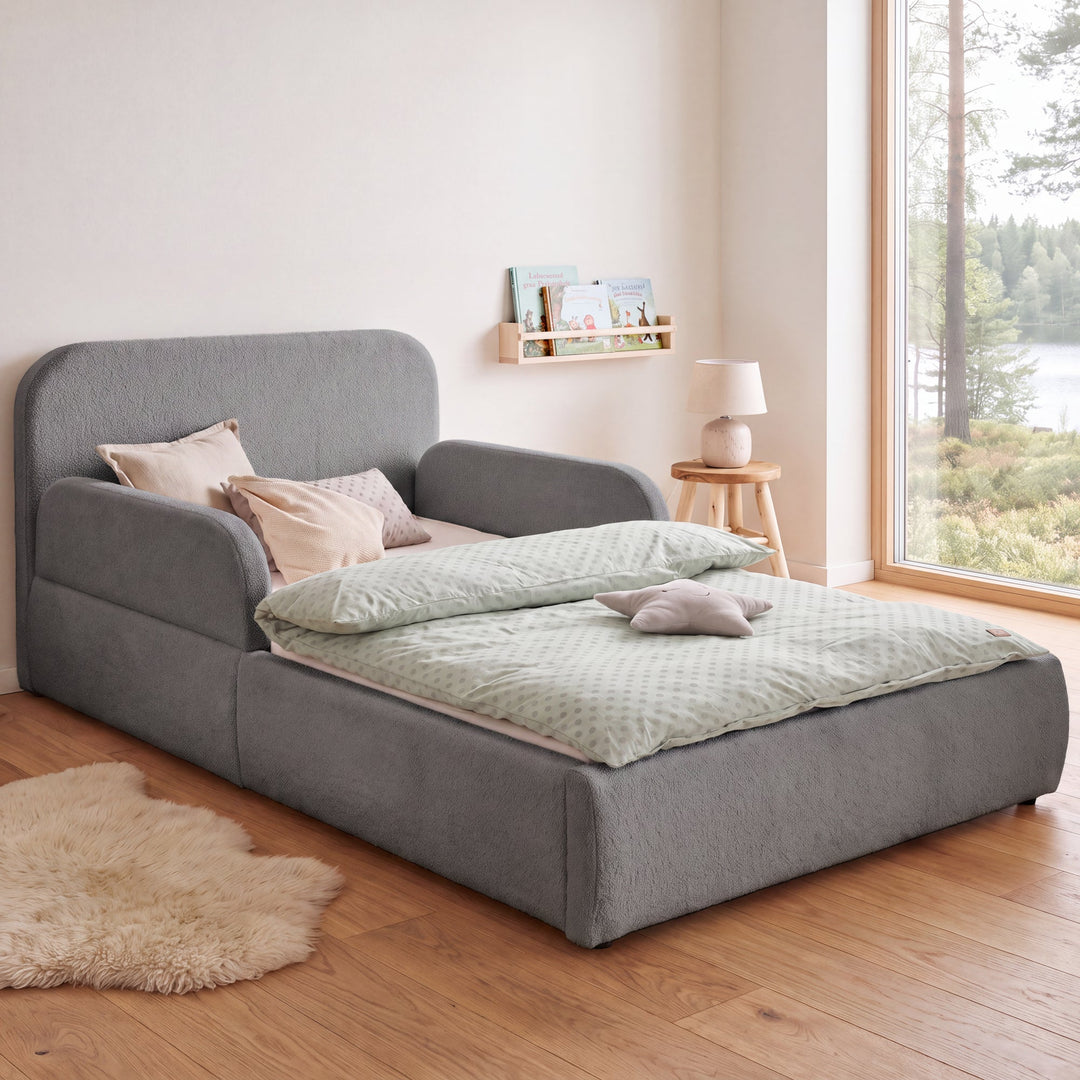 Anthracite roba Little Dream children's bed in a children's room with lake view, bookshelf and sheepskin rug. Partially AI-generated.