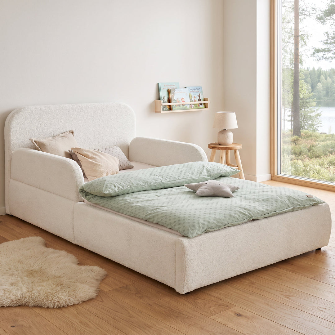 White roba Little Dream children's bed in a children's room with lake view, bookshelf and sheepskin rug. Partially AI-generated.