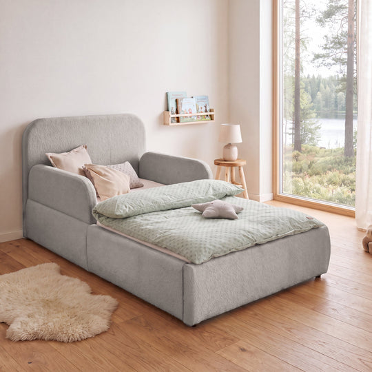 Pannelli laterali grigi chiari sul letto per bambini roba Little Dream in una cameretta con vista lago e libreria. Parzialmente generata con IA.