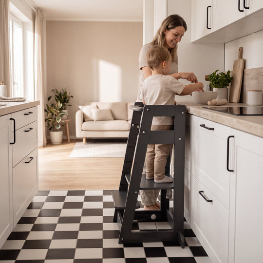 Lifestyle-Bild: Mutter und Kleinkind kochen gemeinsam an einer Küchentheke mit Schachbrettmuster-Boden, das Kind steht im anthrazitfarbenen Lernturm.