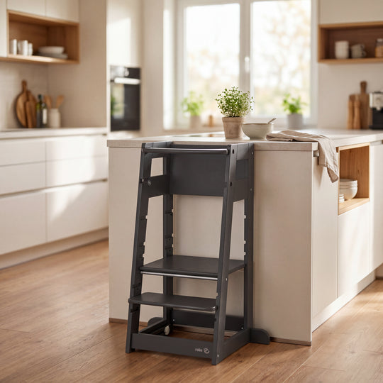 Lifestyle-Bild: leerer Lernturm 'Sit & Step' in Anthrazit an einer Kücheninsel in einer Küche mit Holzschränken.