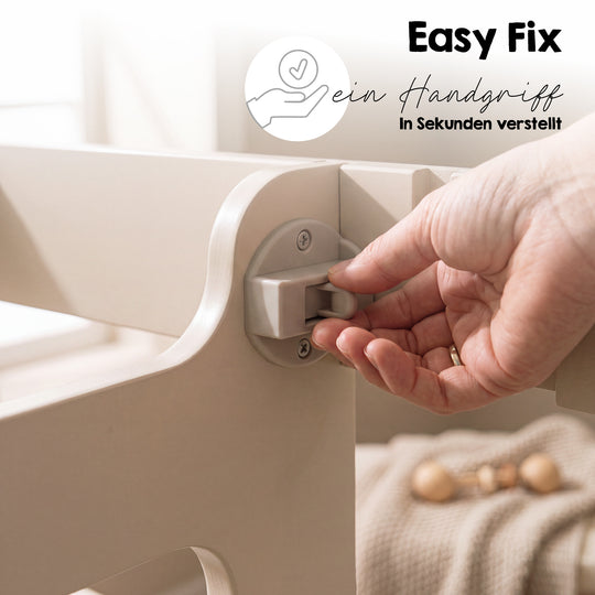 Detailaufnahme mit Schriftzug 'Easy Fix - ein Handgriff - In Sekunden verstellt': Hand bedient den Verstellmechanismus für die Standfläche des Cashmere-farbenen Lernturms.