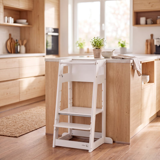 Lifestyle-Bild: Mutter und Kleinkind kochen gemeinsam an einer Küchentheke mit Schachbrettmuster-Boden, das Kind steht im weißen Lernturm.
