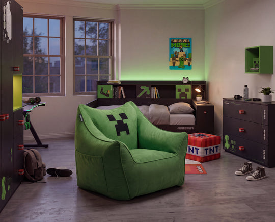 Sillón puf verde con cara de Creeper en una habitación infantil al anochecer con iluminación LED verde y muebles oscuros. Generada íntegramente con IA.